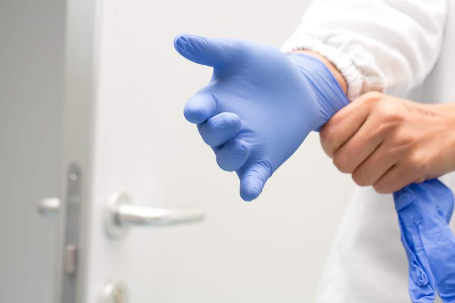 L'utente indossa guanti di gomma (dispositivi di protezione individuale) in ambiente di laboratorio.