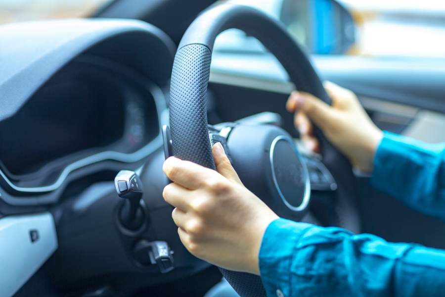 Mani sul volante di un'auto per una guida sicura e sicurezza su strada