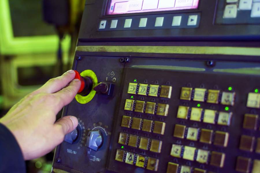Il lavoratore preme il grande pulsante rosso sulla scheda di controllo con molti più pulsanti dopo un errore critico